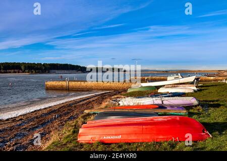 FINDHORN VILLAGGIO MORAY COSTA SCOZIA BARCHE COLORATE ALLINEATE SU IL LITORALE DI GHIACCIO E NEVE SULLA SPIAGGIA DI CIOTTOLI Foto Stock