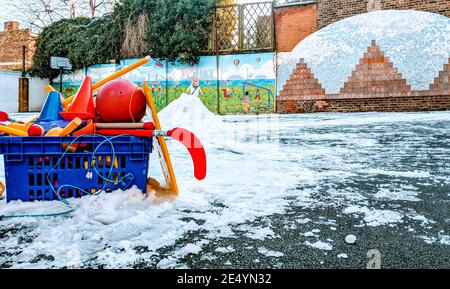Parco giochi della scuola ghiacciato e coperto di neve durante l'inverno del 2021 con una scatola di giocattoli e attrezzature all'aperto per i bambini con cui giocare. Foto Stock