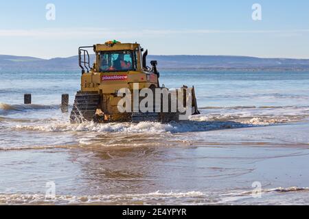 Cat D6T LGP bulldozer crawler caterpillar - programma di rinnovo dei groyne in legno che si svolge sulla spiaggia ad Alum Chine, Bournemouth, Dorset UK a gennaio Foto Stock