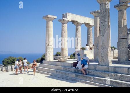 1986 Grecia Tempio di Afaia Aegina il Tempio di Afaia o Afea si trova all'interno di un complesso santuario dedicato alla dea Afaia sull'isola greca di Aegina nel Golfo Saronico. Precedentemente conosciuto come il Tempio di Giove Panhellenius, il tempio dorico è ora riconosciuto come dedicato alla dea madre Aphaia, turisti in un tour guidato godendo la vista del Tempio greco, Aegina Grecia Europa Foto Stock