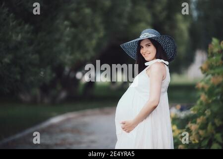 Giovane donna incinta in una giornata estiva nel parco. Mamma in attesa della nascita del bambino Foto Stock
