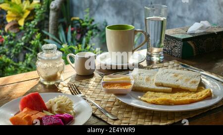 Colazione turistica tradizionale a Bali: Toast, uova strapazzate, caffè e frutta fresca Foto Stock