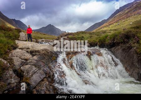 Donna in rosso in piedi a cade a Glen Rosa on Arran Foto Stock