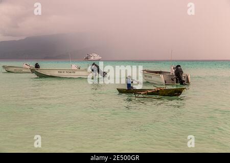 Giovani surfs locali una canoa Outrigger sulla spiaggia di Bougainville, Papua Nuova Guinea Foto Stock