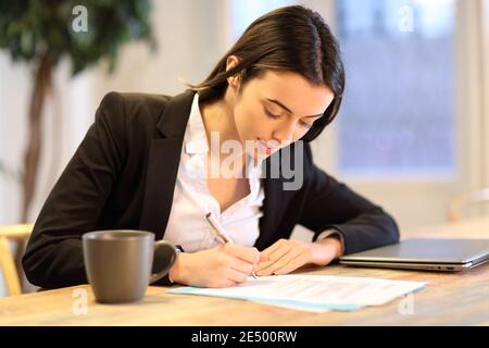 Felice businesswoman firma modulo di carta che lavora in ufficio Foto Stock