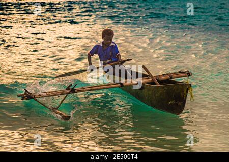 Giovani surfs locali una canoa Outrigger sulla spiaggia di Bougainville, Papua Nuova Guinea Foto Stock