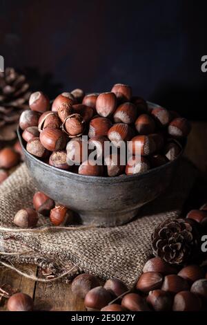 Nocciole sgusciate fresche in una vecchia ciotola in metallo su sfondo di legno. Foto Stock