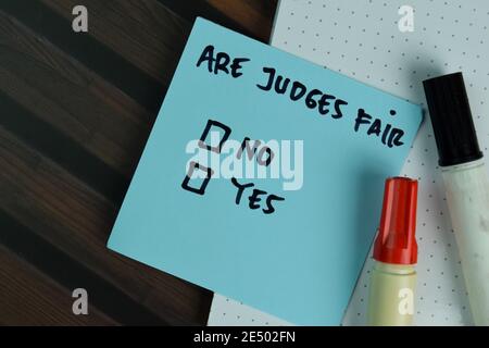 Sono Judges Fair scrivere su note appiccicose e supportati da servizi aggiuntivi scrivere su una nota appiccicosa isolato su legno tavolo. Foto Stock