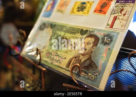 Aqaba, Giordania - 17 gennaio 2020: Ritratto di Saddam Hussein sulle banconote irachene da 25 dinari d'epoca, con francobolli dell'Iraq in esposizione a souvenir sho Foto Stock