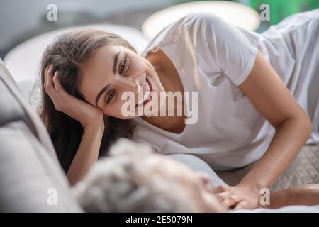 Donna che parla con un uomo mentre si trova nel letto Foto Stock