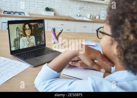 Giovane insegnante di sesso femminile che comunica con la studentessa tramite video chat durante la lezione online durante il blocco Foto Stock