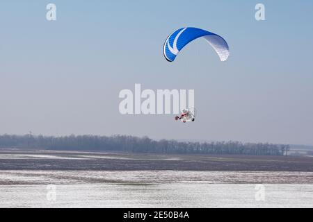 Paramotore visto dal cielo in Francia volare su neve campi in inverno con orizzonte e cielo blu Foto Stock