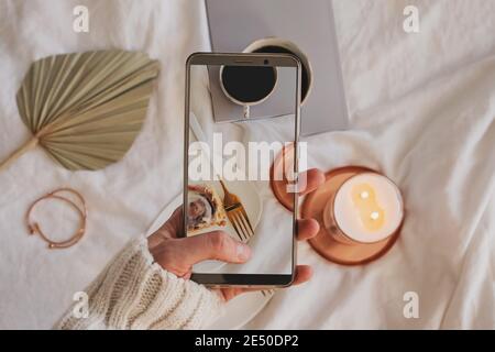 Donna mano che scattano foto della composizione con la cottura alla cannella, il caffè e la candela che brucia Foto Stock