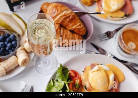 Bicchiere di champagne da vicino sul tavolo con colazione diversa e piatti del brunch Foto Stock