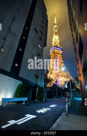 Ampio angolo di vista notturna di una strada che porta al Torre di Tokyo illuminata con luce arancione Foto Stock