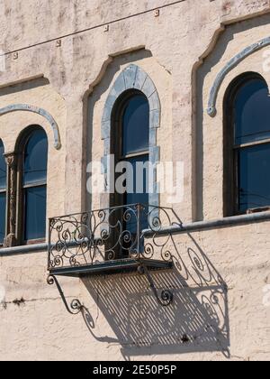 griglia in stile balcone su una grande finestra o porta il lato di un muro di stucco con ombra da luce solare intensa Foto Stock