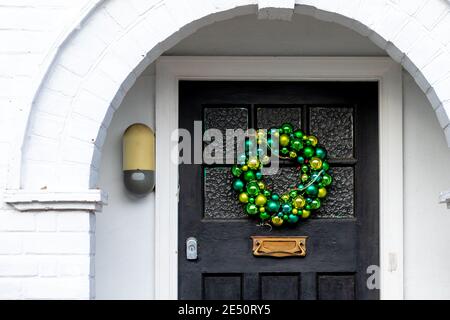 I baubles verdi formano una corona di Natale su una porta anteriore sotto un alcova Foto Stock