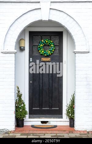 I baubles verdi formano una corona di Natale su una porta anteriore sotto un alcova Foto Stock