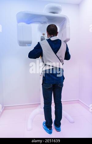 Uomo in piedi su una macchina a raggi X dentale. Foto Stock