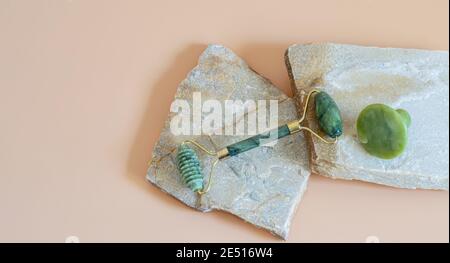 Rullo viso Gua sha per massaggio su podio pietre naturali. Trattamento di sollevamento e tonificazione. Cure sanitarie, concetti di benessere. Foto Stock