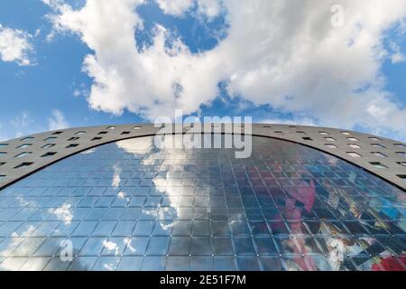 Vista grandangolare simmetrica di una moderna struttura in vetro riflettente il cielo estivo blu con nuvole soffici sopra Foto Stock