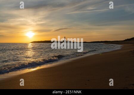 Tramonto tranquillo sulla spiaggia di Playa de Maria Sucia con Il faro di Cape Trafalgar sullo sfondo Foto Stock