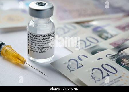 Flaconcino di vaccino originale Pfizer BioNTech COVID-19 posto accanto alle note della libbra britannica. Foto di vaccino reale. Messa a fuoco selettiva. Stafford, Regno Unito - Janu Foto Stock