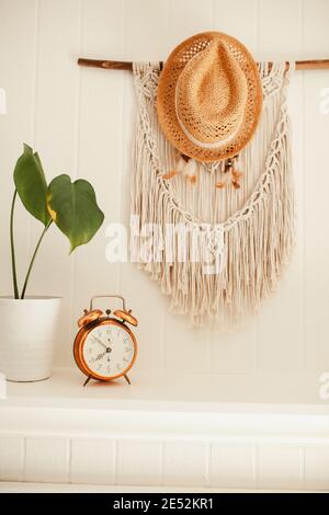 Camino in legno bianco con macrame e sogni catcher sulla parete, con piante casa e allarme rame vintage sulla mensola fuoco posto Foto Stock