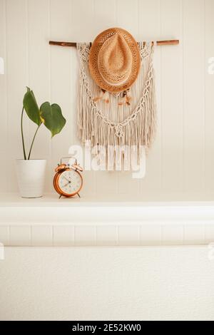 Camino in legno bianco con macrame e sogni catcher sulla parete, con piante casa e allarme rame vintage sulla mensola fuoco posto Foto Stock