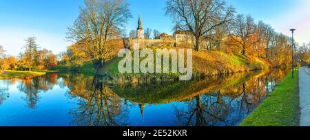 Paesaggio panoramico con parco e laghetto lungo le mura medievali della città vecchia in autunno. Tallinn, Estonia Foto Stock