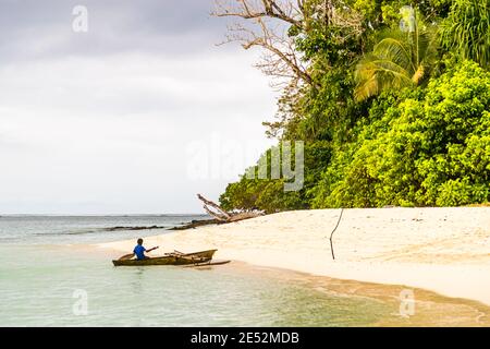 Giovani surfs locali una canoa Outrigger sulla spiaggia di Bougainville, Papua Nuova Guinea Foto Stock