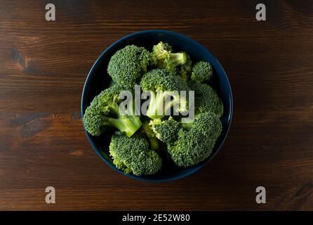 Tagliare i broccoli in una ciotola posta su uno sfondo di legno. Vista dall'alto Foto Stock