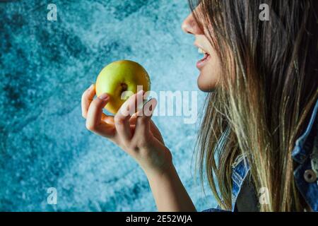 Donna che mangia mela su sfondo blu Foto Stock