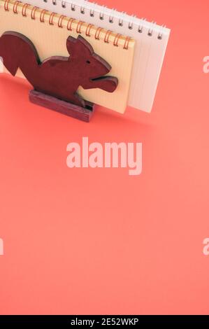 Scatto isolato verticale dei taccuini nello scoiattolo di legno supporto carta su sfondo rosa- Foto Stock