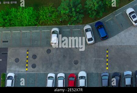 Vista sopra le auto parcheggiate nel parcheggio dell'appartamento. Parcheggio in cemento con vista aerea, con dislivello di velocità vicino a alberi verdi nel parco. Foto Stock