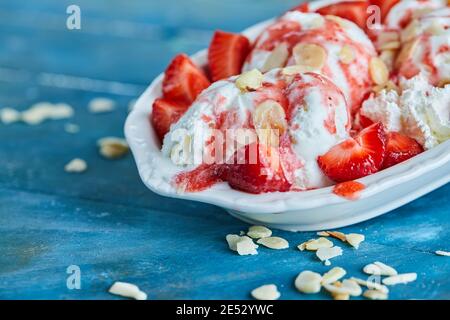 Gelato alla vaniglia con fragole cosparse nella piastra bianca Foto Stock