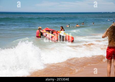 Volontari salvataggio surf lifesavers lanciare gonfiabile rosso zodiac salvataggio surf Barca a Bilgola Beach a Sydney, NSW, Australia Foto Stock