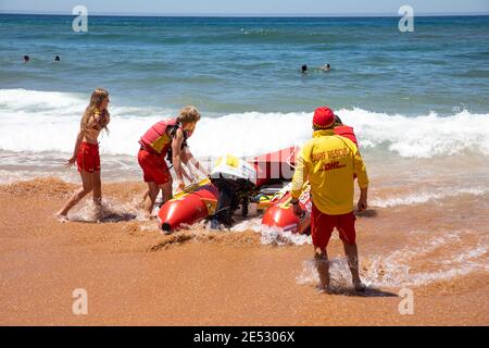 Volontari salvataggio surf lifesavers lanciare gonfiabile rosso zodiac salvataggio surf Barca a Bilgola Beach a Sydney, NSW, Australia Foto Stock