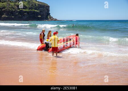 Volontari salvataggio surf lifesavers lanciare gonfiabile rosso zodiac salvataggio surf Barca a Bilgola Beach a Sydney, NSW, Australia Foto Stock