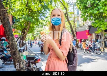 Donna che usa l'app del telefono per il servizio di corsa in taxi o la guida di corsa di lettura che indossa una maschera medica durante il coronavirus COVID-19. Ragazza turistica Foto Stock