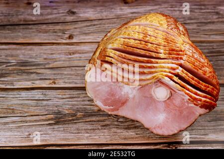 Prosciutto di maiale a fette a spirale su sfondo di legno. Pasto di festa. Foto Stock