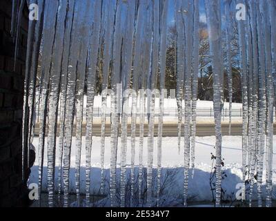 Lunghe Icicles si aggirano davanti a una finestra che guarda In un giorno innevato Foto Stock