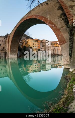 Vista grandangolare del ponte del Diavolo a Fossombrone, specchiato su acqua stalla Foto Stock