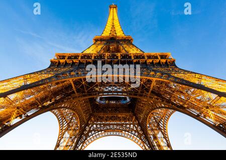 Vista grandangolare della Torre Eiffel illuminata dal giallo luce come visto dal basso all'ora blu Foto Stock