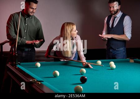 donna che riceve consigli su tiro palla da biliardo mentre si gioca con gli amici, concentrato sul gioco di sport Foto Stock