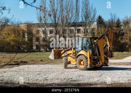 Dneprorudnoe, Ucraina - Aprile 08 2020: Un trattore versa la ghiaia dalla benna Foto Stock