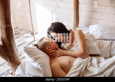 Giovane coppia innamorata, uomo e donna, si trova a letto sotto una coperta  bianca. Si guardano l'un l'altro con tenerezza Foto stock - Alamy