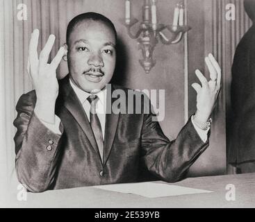 Martin Luther King, ritratto della testa e delle spalle, seduto, rivolto verso la parte anteriore, mani estese verso l'alto, durante una conferenza stampa. STATI UNITI. 6 novembre 1964 Foto Stock