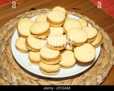 Gli alfajores tradizionali in Argentina, Perù e Uruguay consistono di due biscotti dolci rotondi fatti di farina di grano o amido di mais Uniti insieme con il dul Foto Stock