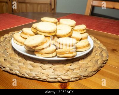 Gli alfajores tradizionali in Argentina, Perù e Uruguay consistono di due biscotti dolci rotondi fatti di farina di grano o amido di mais Uniti insieme con il dul Foto Stock